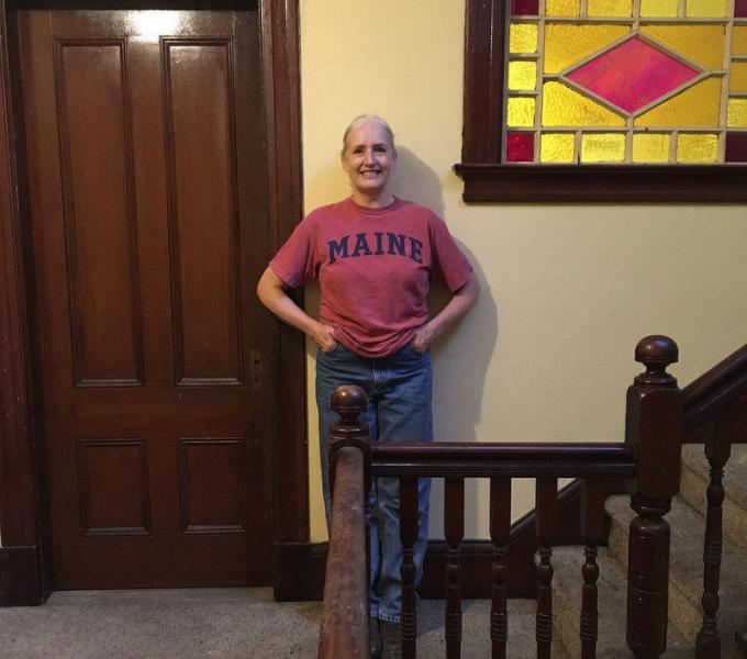 Bettyann Sheats stands in one of her apartment buildings in Lewiston, in front of a staircase that's tested positive for lead.
